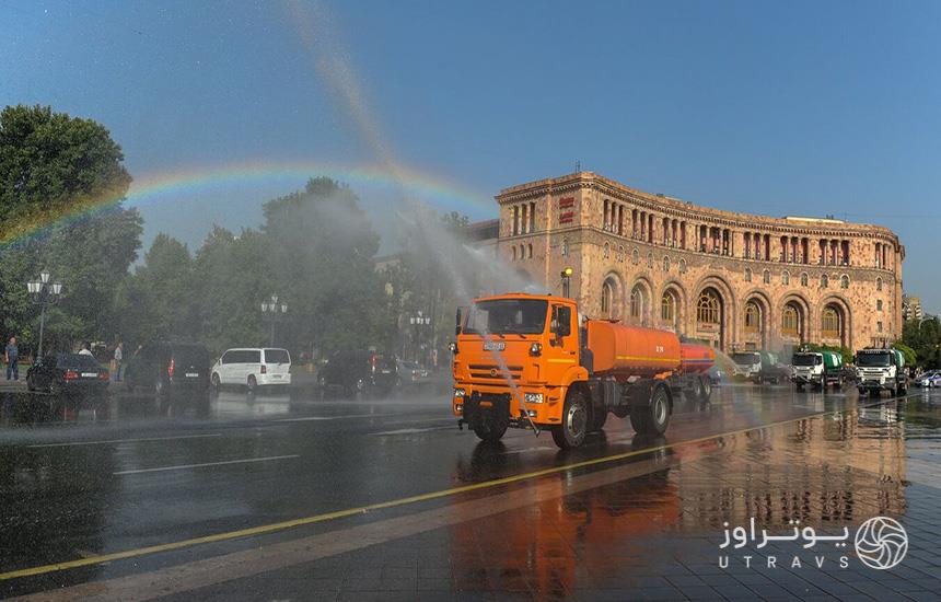 یک ماشین شهرداری نارنجی‌رنگ درحال آب‌پاشی در جشن آب ارمنستان